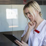 Bildet viser en kvinnelig sykepleier som bruker et nettbrett