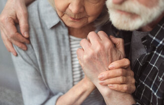 Bildet viser en eldre mann som holder rundt en eldre kvinne