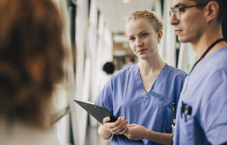 Bildet viser sykepleiere som lytter til en pasient.