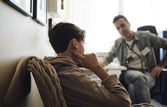 Bildet viser en ung gutt i samtale med en helsesykepleier.