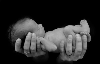 Et prematurt barn som holdes i sin fars hender.