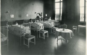 Bildet viser en sykehussal med flere senger og barn.