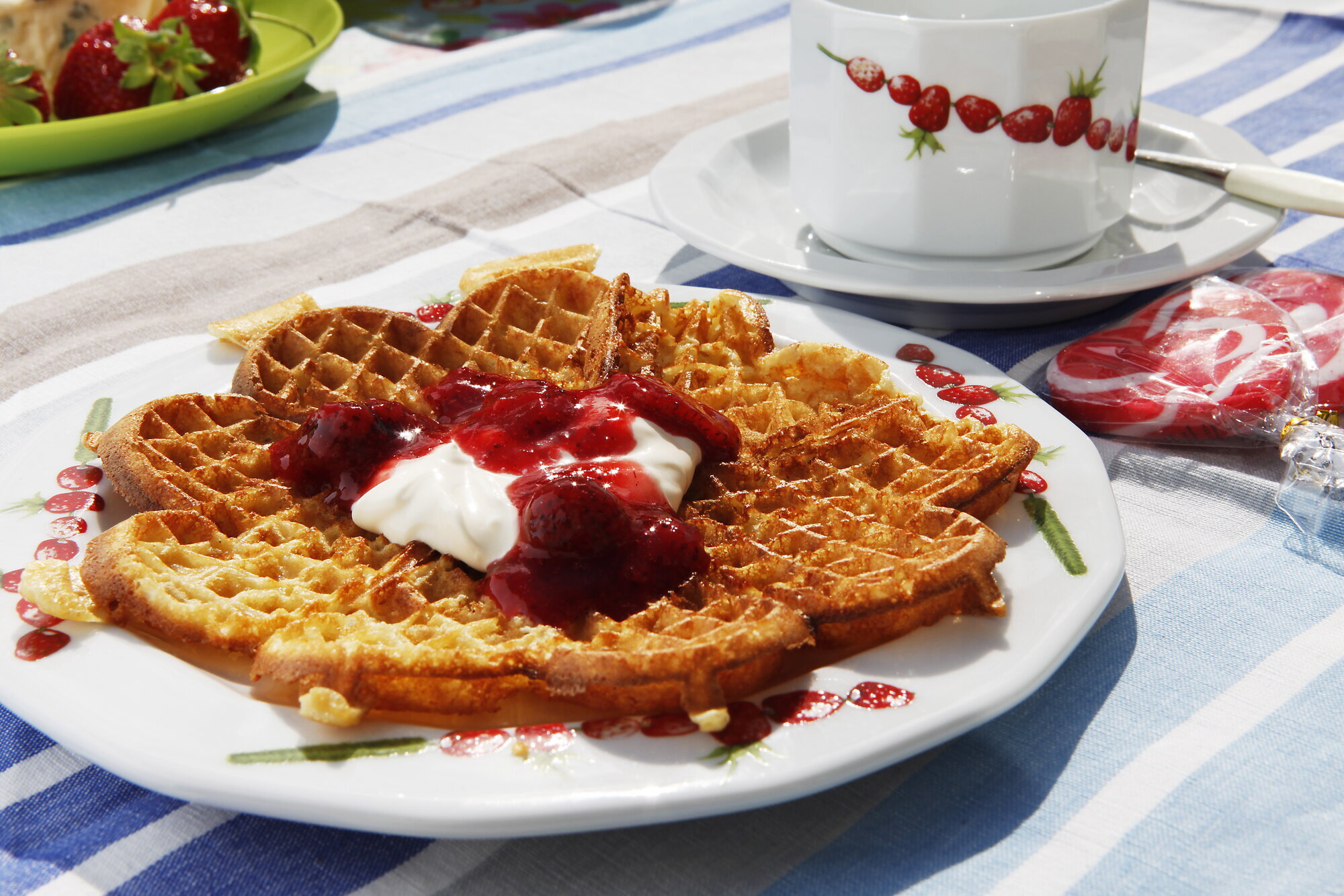 Det skal noe til motstå duften av nystekte vafler. Bildet viser en vaffelplate med syltetøy og rømme.