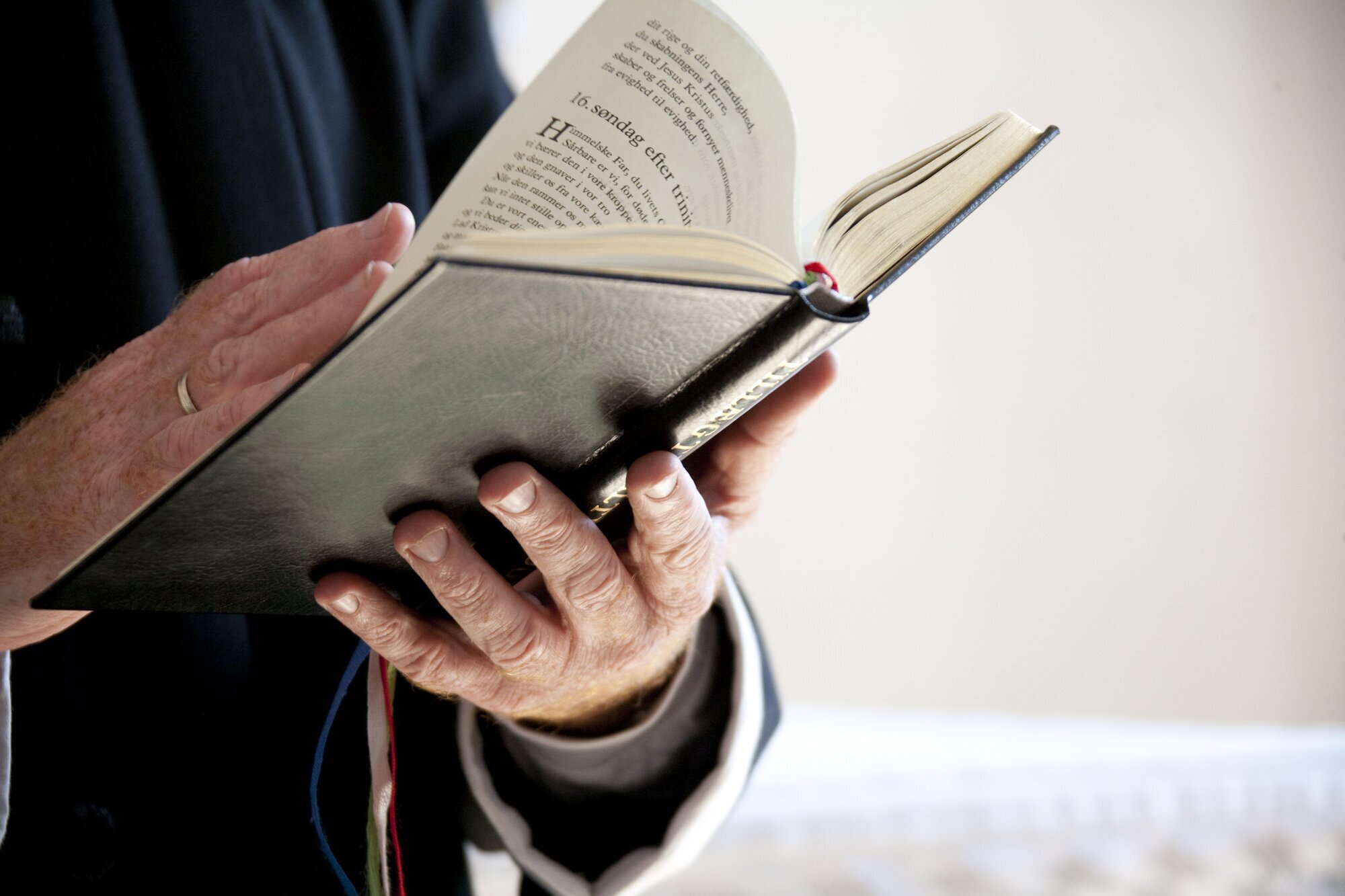 Prest Prest som holder en salmebok i hendene