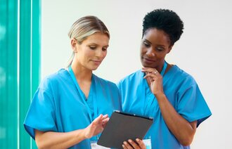 Bildet viser to sykepleiere som bruker en iPad