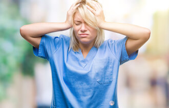 Bildet viser en sykepleier som er stresset og fortvilet