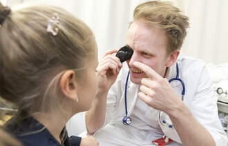 Bilde viser en fastlege som undersøker en liten jente Bilde viser en fastlege som undersøker en liten jente